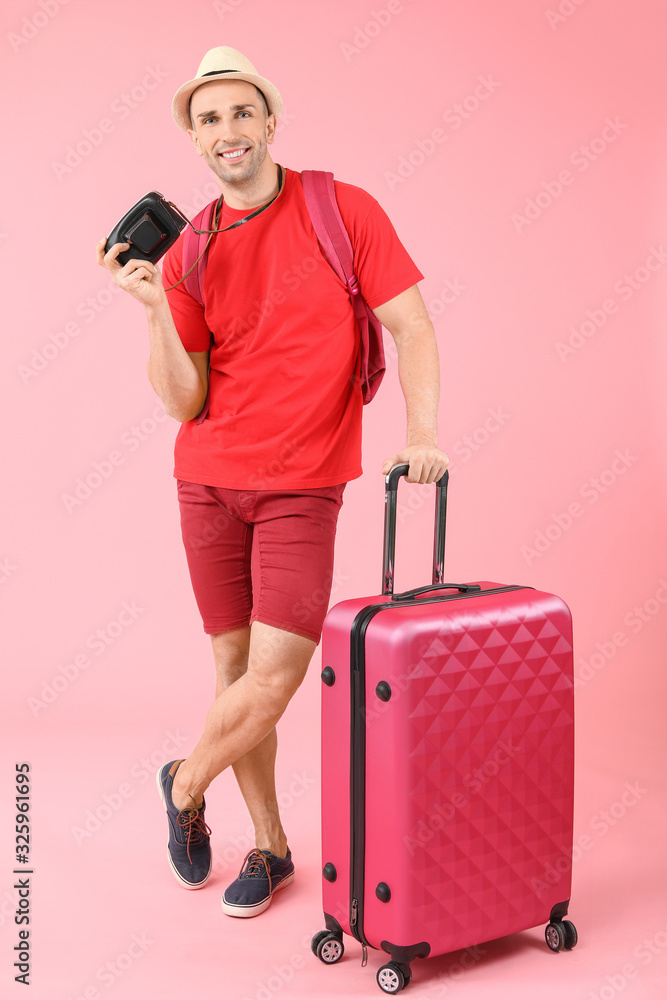 Male tourist with luggage on color background