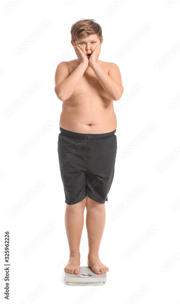 Overweight boy standing on scales against white background