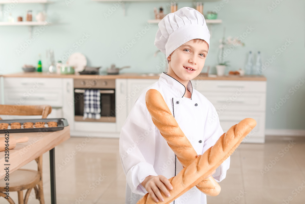 Cute little chef with bread in kitchen