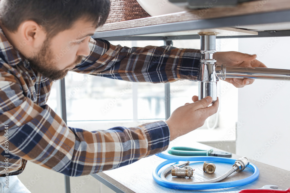 Plumber repairing sink in bathroom