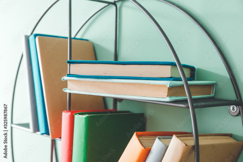 Shelf with books on color wall