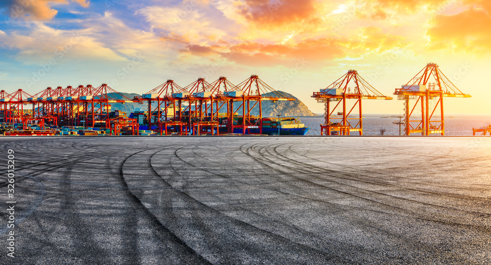 Empty race track and industrial container freight port at beautiful sunset in Shanghai.