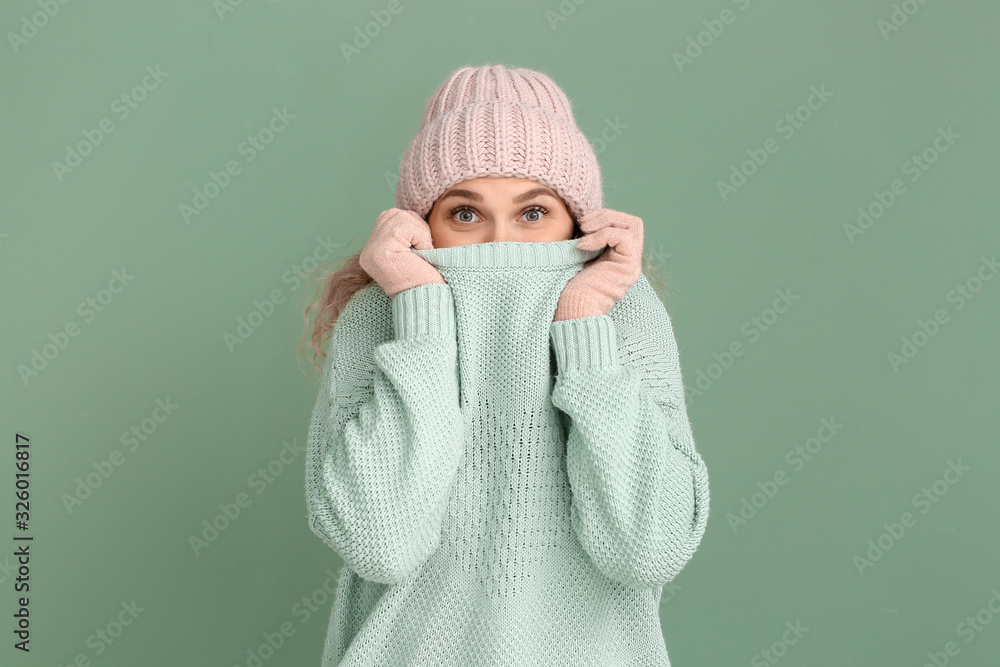 Beautiful young woman in warm sweater on color background