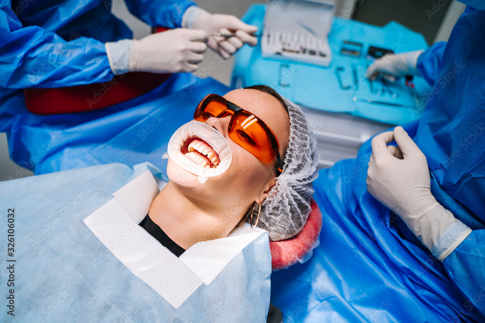 Dentists very carefully check up and repair tooth of young female patient in safety glasses.