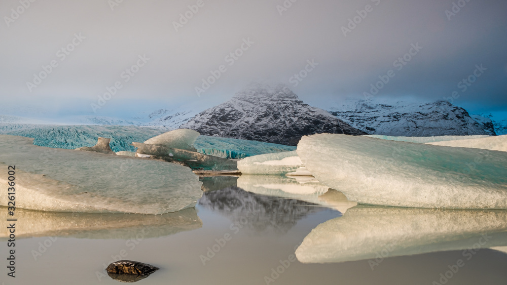 Icebergs and mountains reflected in a lake. Iceland, winter.