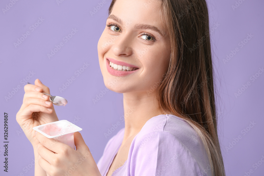 Young woman with tasty yogurt on color background