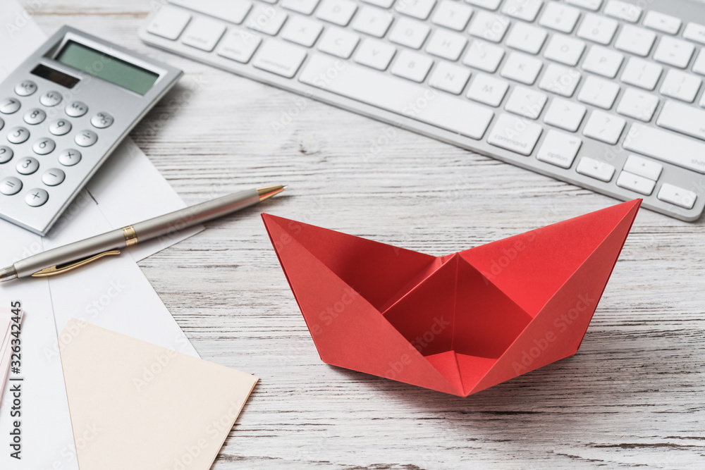 Businessman workspace at desk with red paper ship