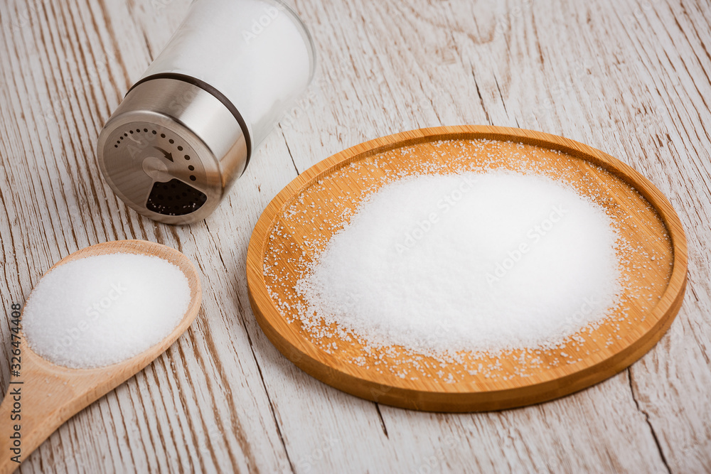 White sea salt for cooking food in Small glass bottles, wooden spoons, and trays on Old wooden table