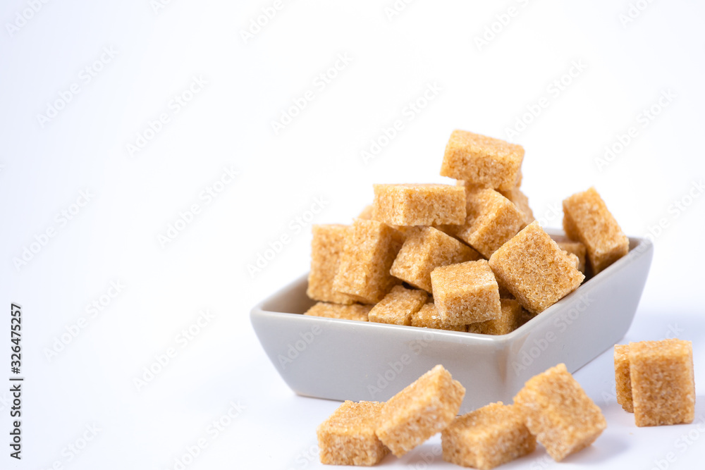 Brown sugar in a square cup on a white background, healthy sugar is used for cooking or desserts.