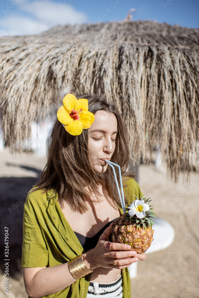 阳光明媚的一天，一位年轻漂亮的女士在海滩度假胜地喝着异国情调的鸡尾酒。概念