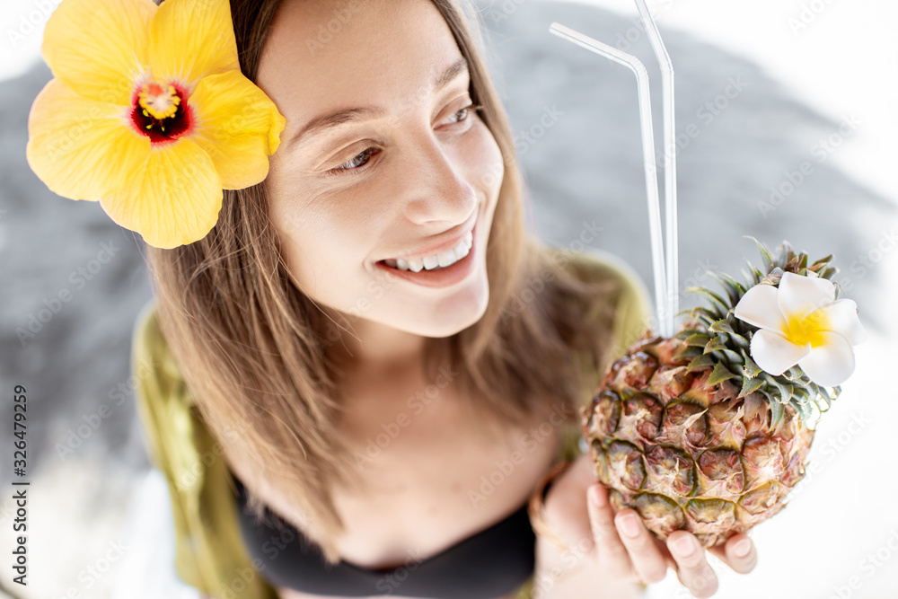 Portrait of a beautiful young smiling woman with exotic cocktail at the beach resort on a sunny day.