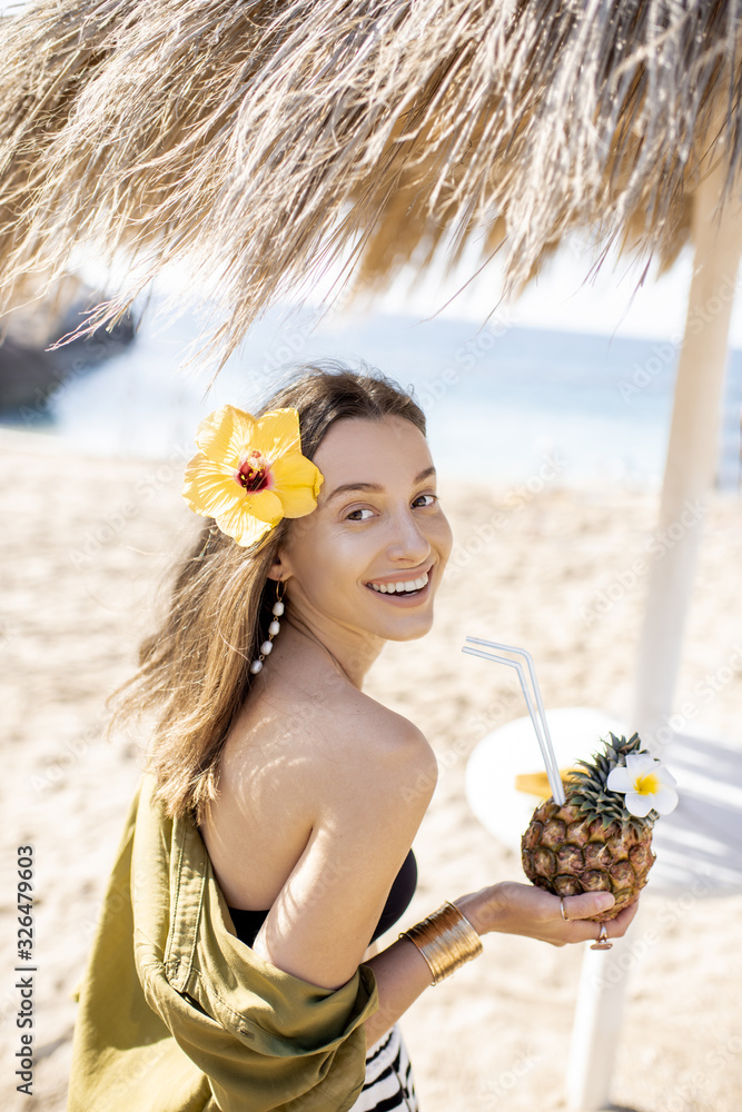 阳光明媚的一天，一位年轻漂亮的女士在海滩度假胜地喝着异国情调的鸡尾酒。概念