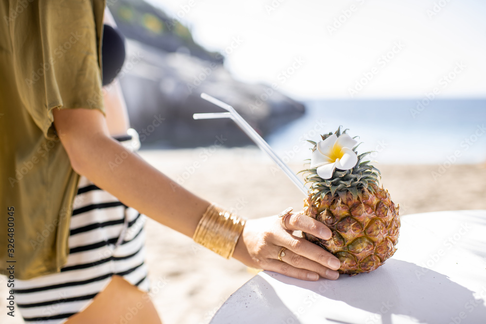 Beautiful young woman standing with exotic cocktail at the beach resort on a sunny day. Concept of e