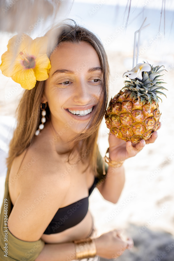 Facial portrait of a cute summer girl with pineapple fruit at the beach resort on a sunny day. Conce