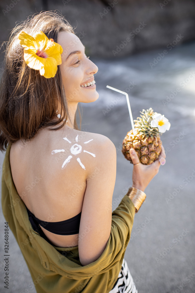 Portrait of a beautiful smiling woman with exotic cocktail at the beach on a sunny day. Concept of a