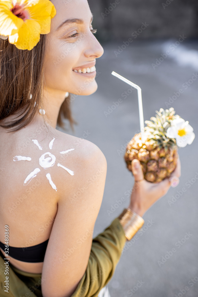 Portrait of a beautiful smiling woman with exotic cocktail at the beach on a sunny day. Concept of a