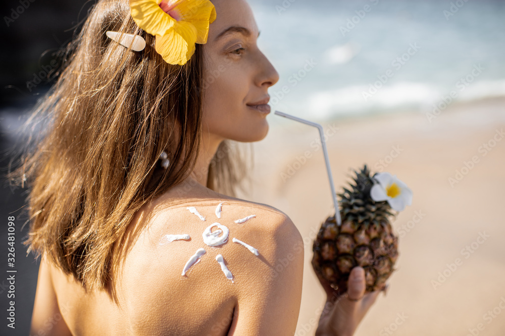 Portrait of a beautiful smiling woman with exotic cocktail at the beach on a sunny day. Concept of a