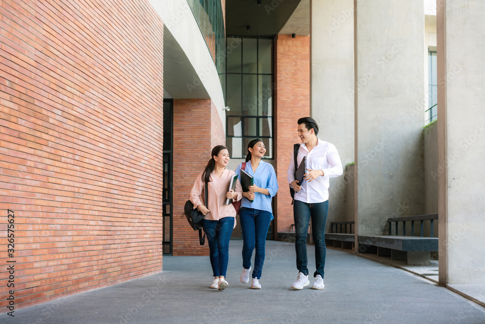 大学课间休息时，三名亚裔学生在大学礼堂一起散步和交谈。