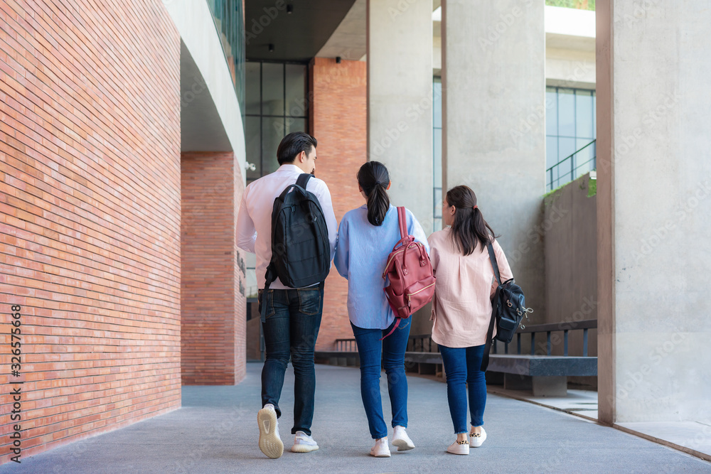 大学课间休息时，三名亚裔学生在大学礼堂一起散步和交谈。