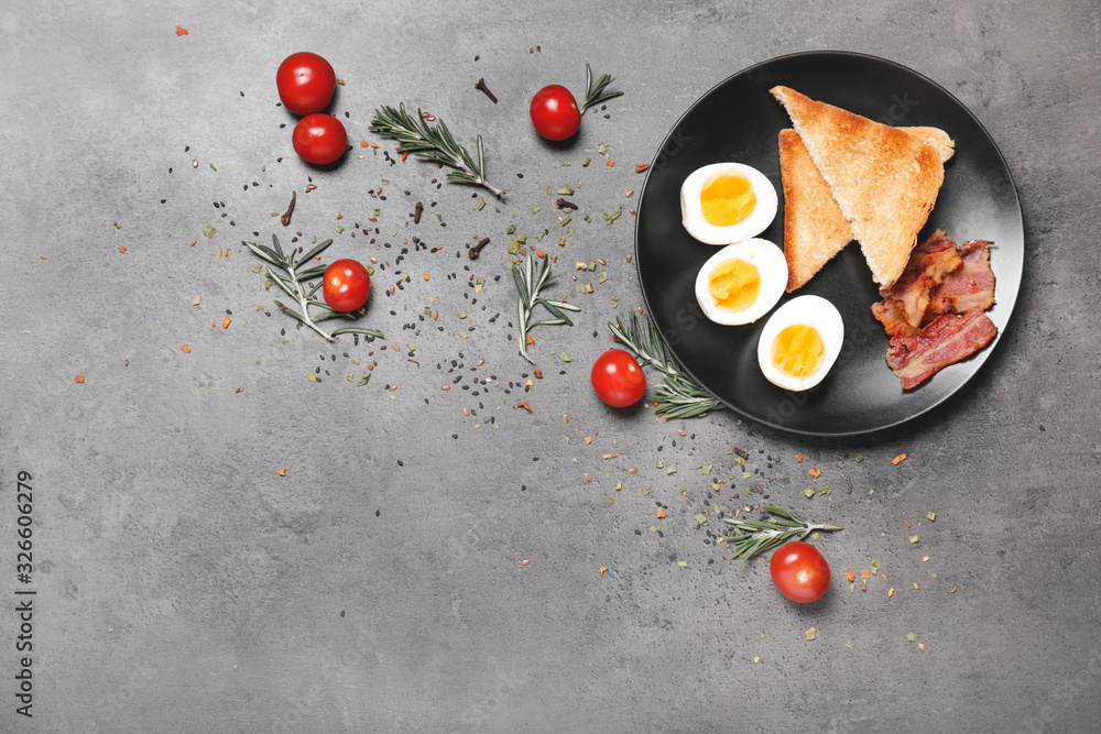 Plate with boiled eggs, bacon and toasted bread on dark background