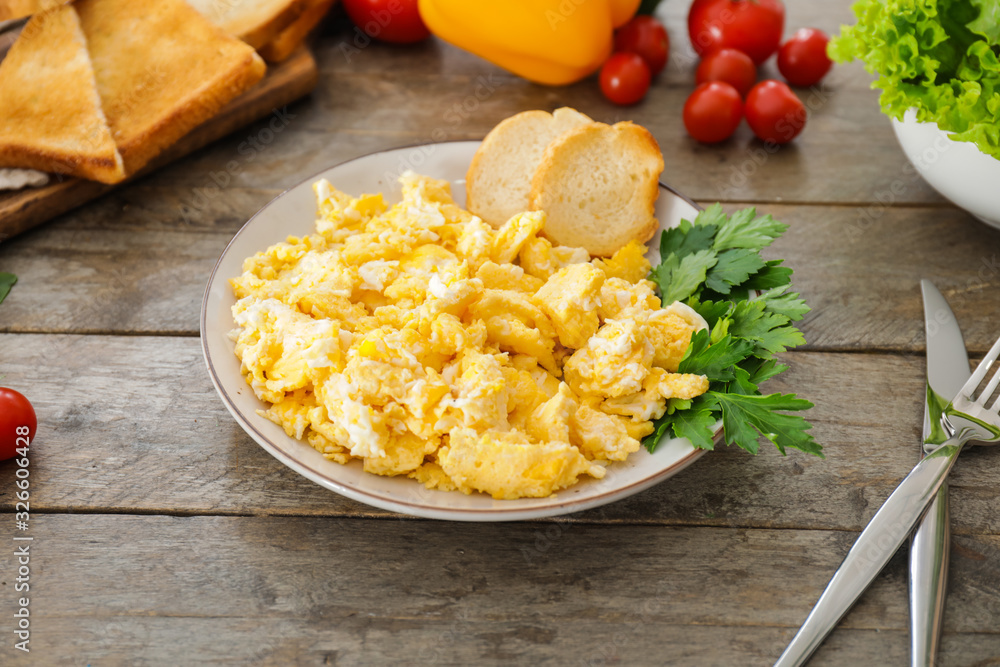 Plate with scrambled egg on table