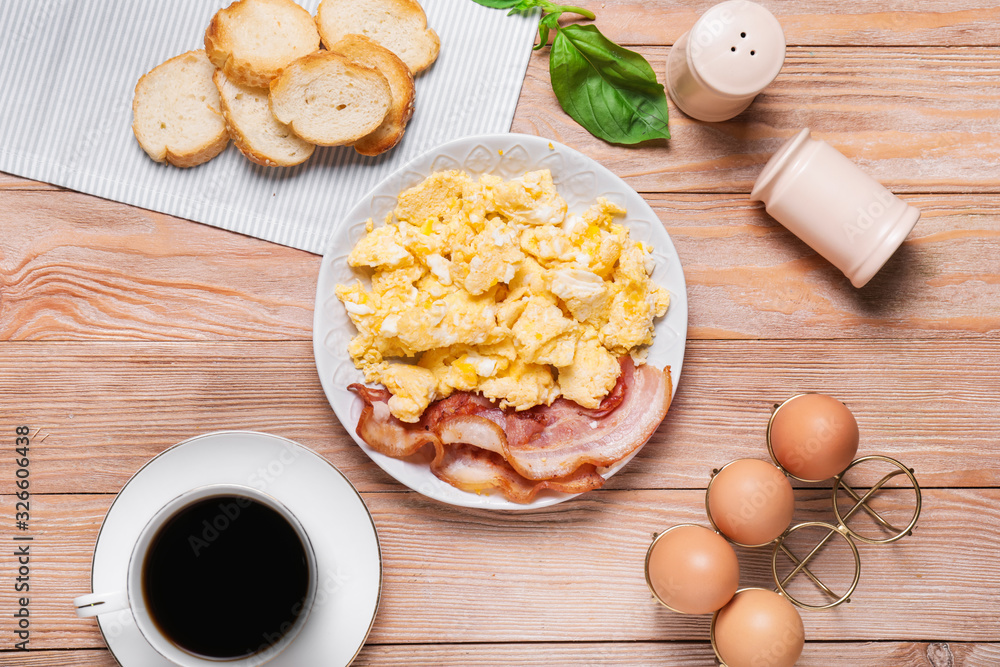 Plate with scrambled egg and bacon on table