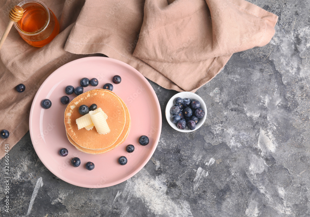 Tasty pancakes with butter and berries on grey background