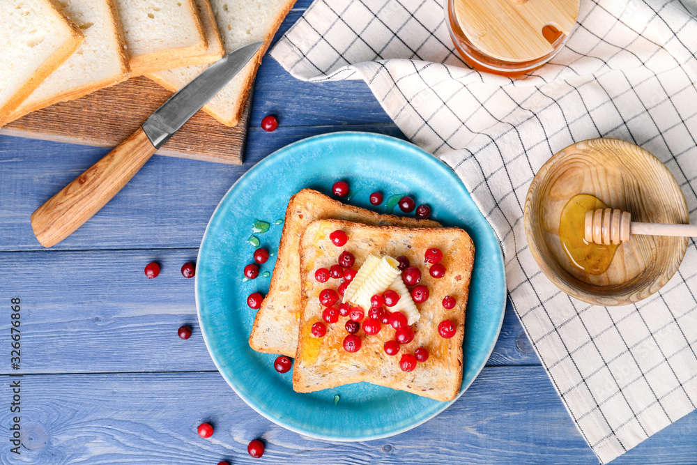 Tasty toasted bread with honey, butter and berries on table