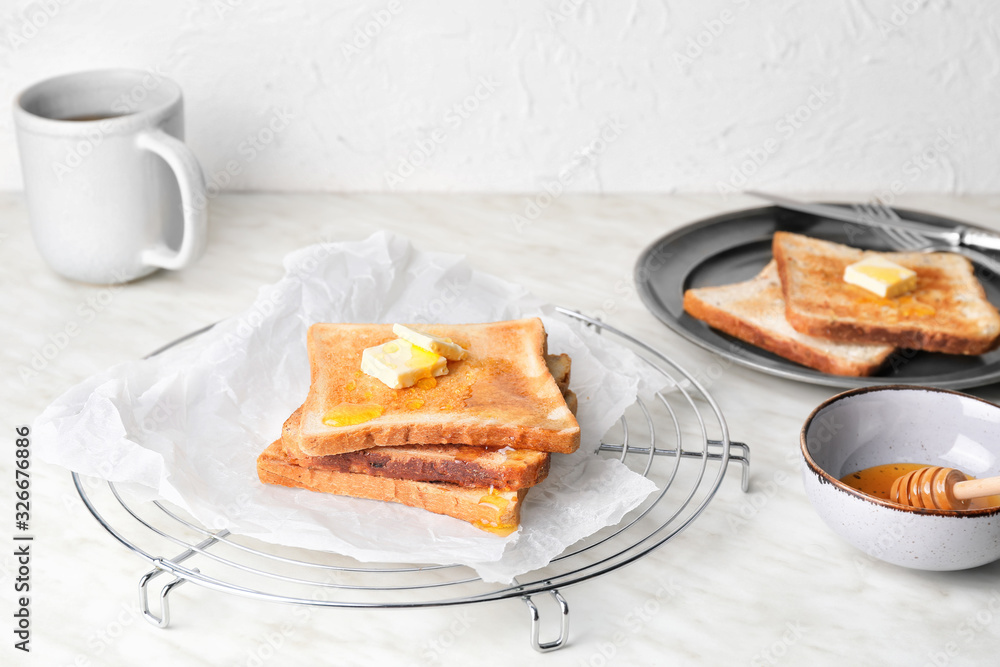 Tasty toasted bread with honey and butter on cooling rack