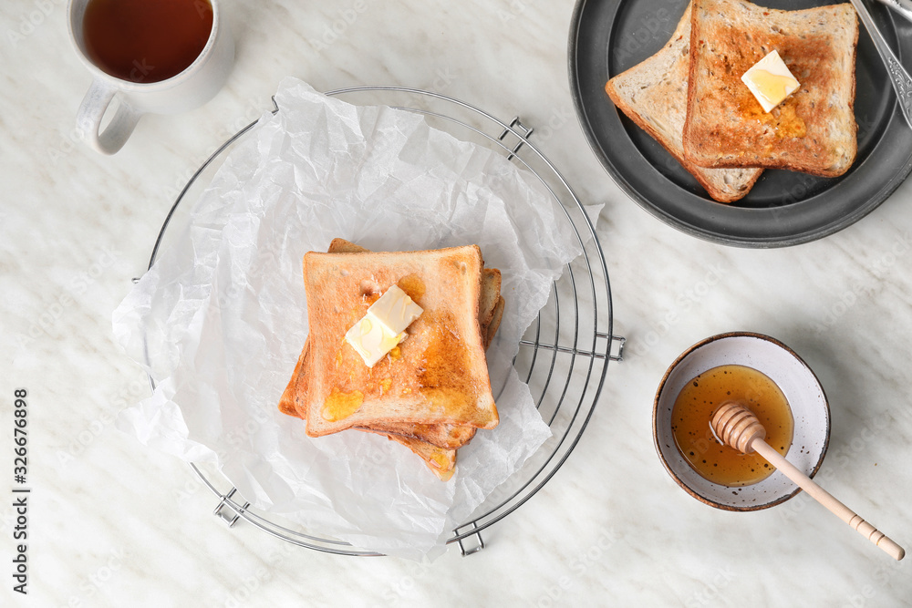 Tasty toasted bread with honey and butter on white background