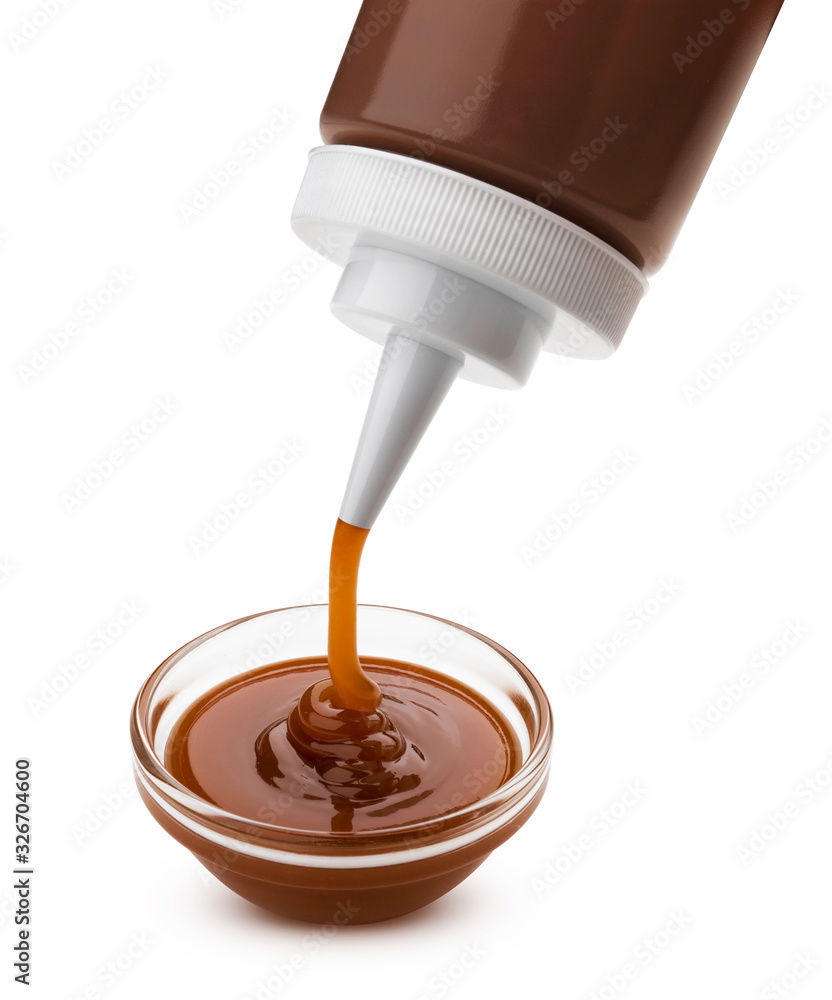 Pouring caramel sauce with bottle isolated on white background