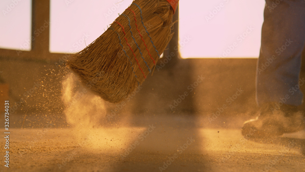 LOW ANGLE: Worker sweeps the dusty floor after long day at the construction site