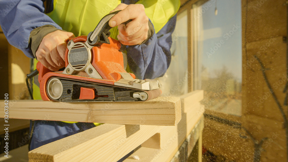 CLOSE UP: Unrecognizable contractor buffs a wooden beam with an electric sander