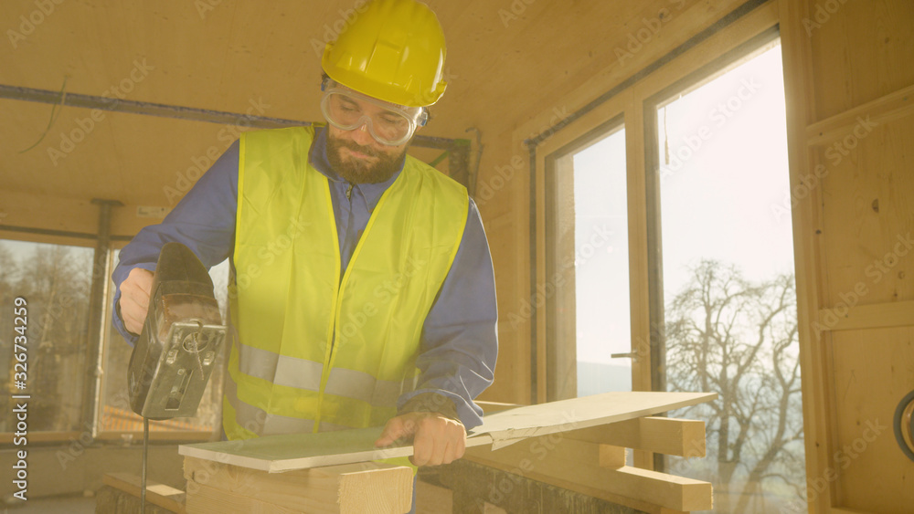 LENS FLARE: Worker building a hardwood house is trimming a gypsum wallboard.