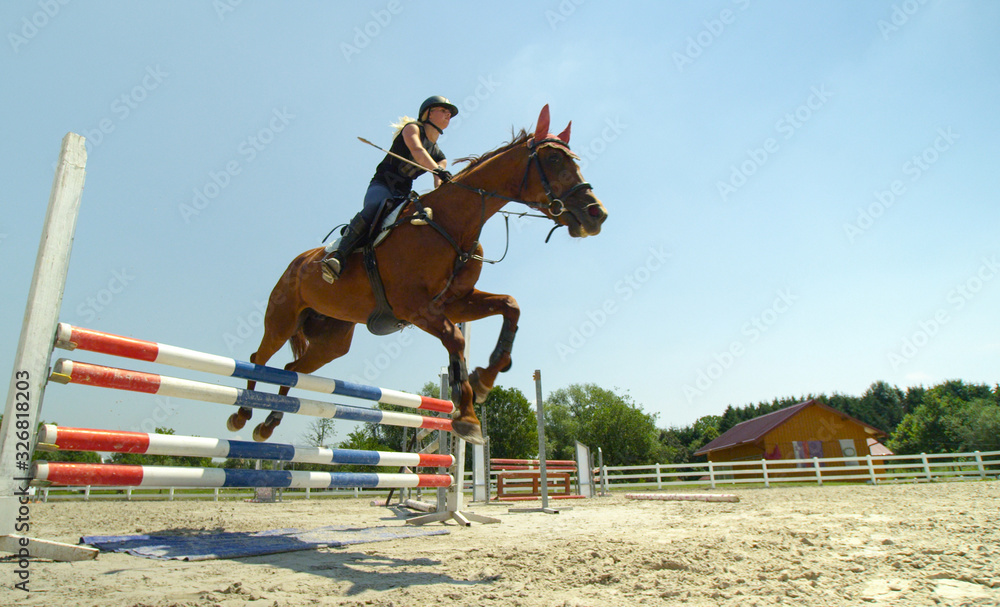 Brave girl rider jumping pole fence with her horse in paddock