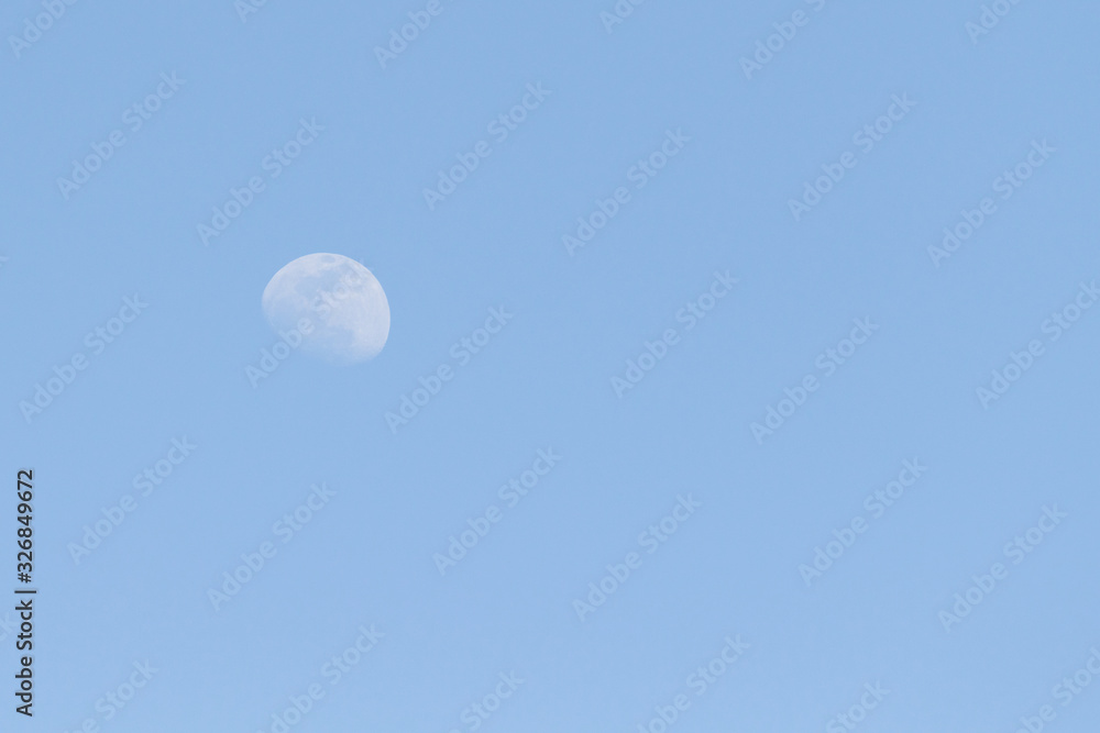 The moon against the blue sky day.