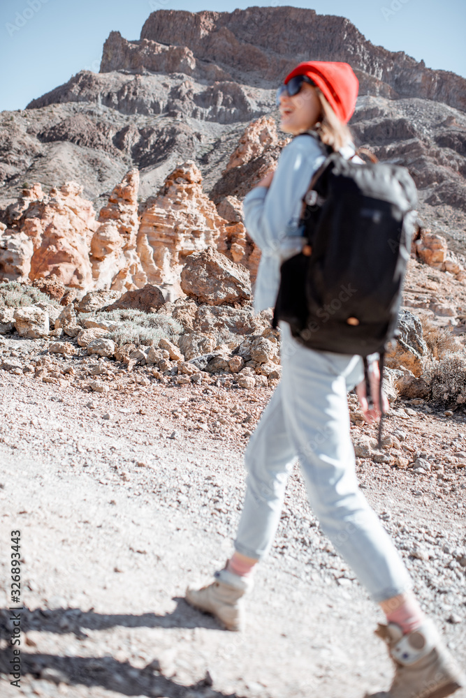 一名女子在阳光明媚的日子里在岩石地形上徒步旅行，同时在特内里费岛的火山谷旅行