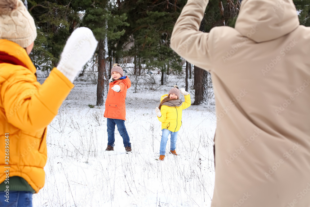 Happy family playing snowballs in park on winter day