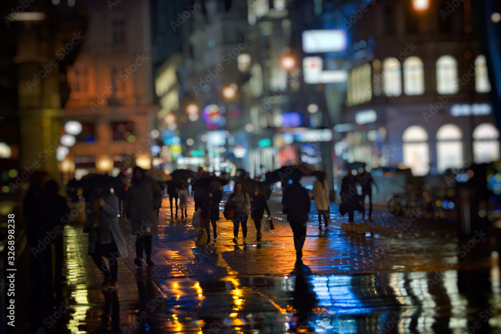 维也纳市雨夜步行的行人