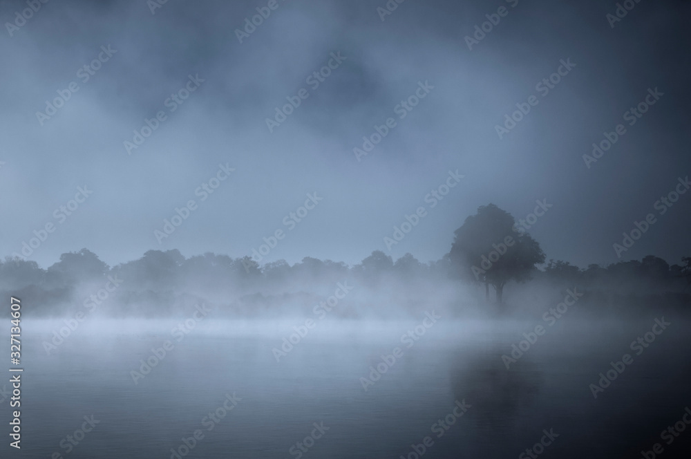 雾中的河流景观/晨雾中的深蓝色河流景观。