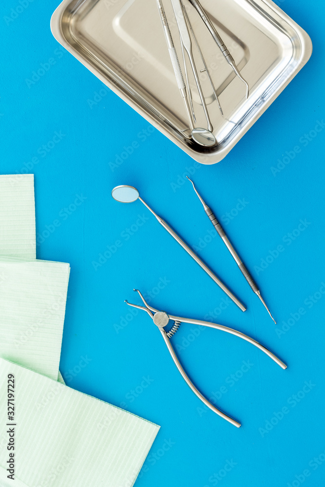 Stomatological tools in tray on dentists desk on blue background top-down