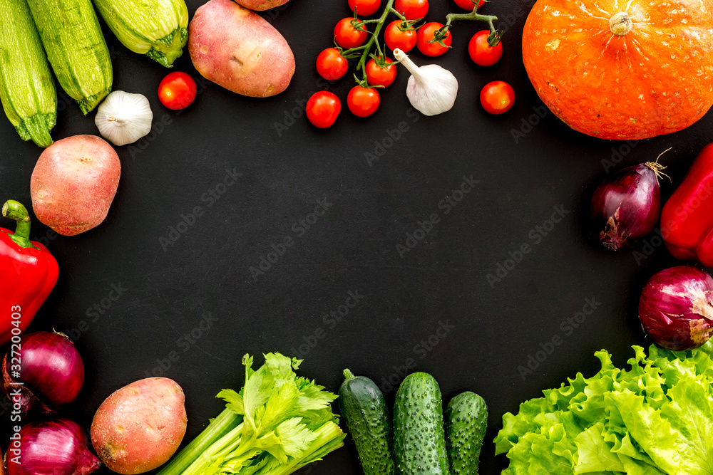 Set of autumn vegetables - potato, cucumber, carrot, greenery - on black background top-down copy sp