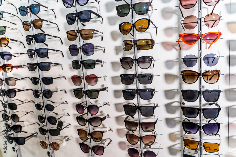 Sunglasses in the shop display shelves. Stand with glasses in the store of optics.