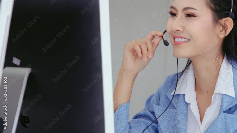 Customer support agent or call center with headset works on desktop computer while supporting the cu