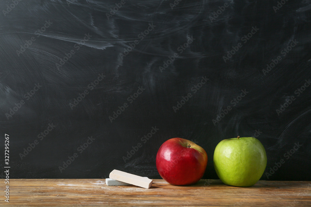 Apples and chalk on table in classroom