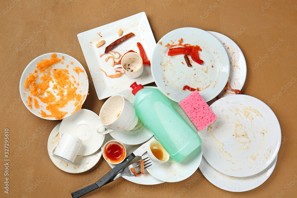 Dirty empty tableware and dish wash detergent on color background