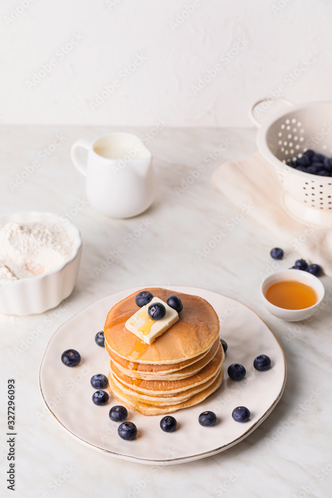 Tasty pancakes with honey, butter and berries on table