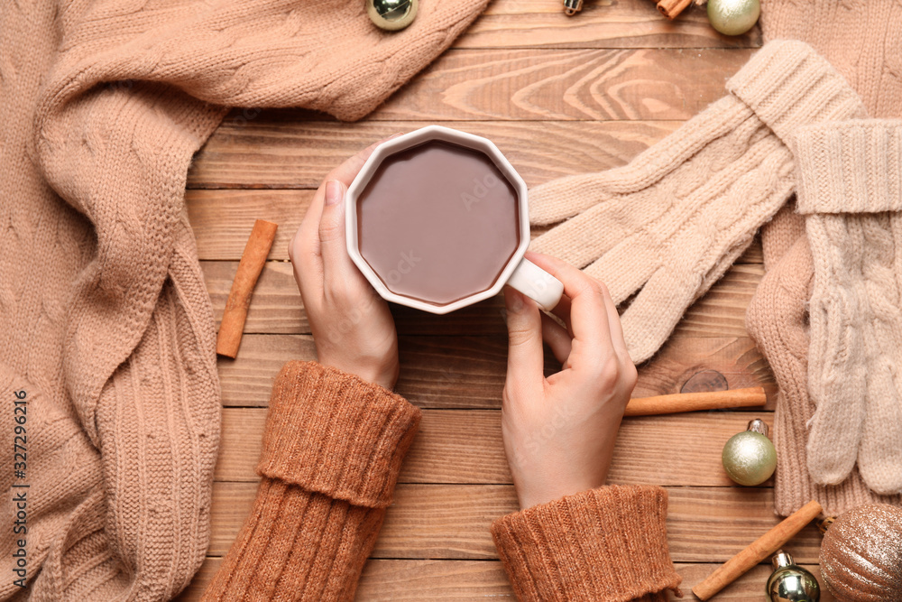 Female hands with cup of hot chocolate on wooden background