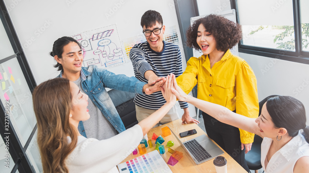 Young Asian people stacking hands for teamwork concept