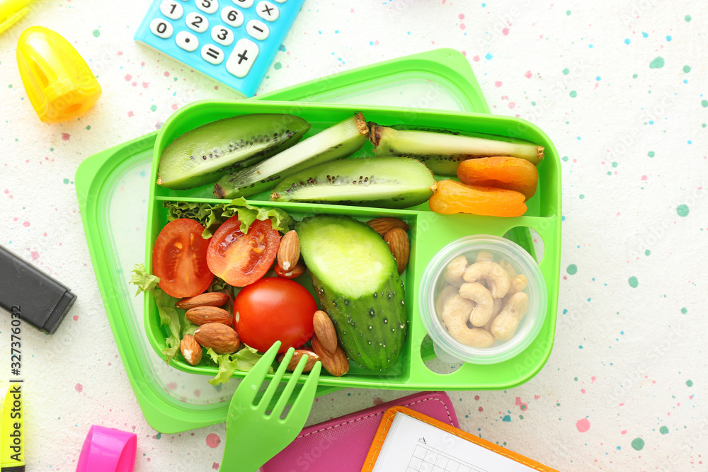 School lunch box with tasty food and stationery on table